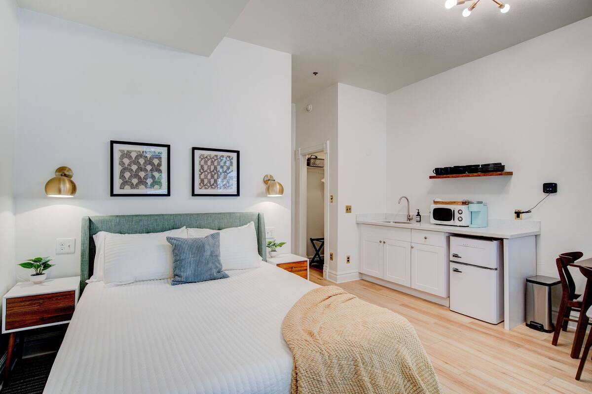 Una camera da letto moderna con un letto, comodini e un angolo cottura.