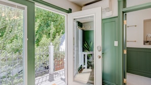 A room with a sliding glass door leading to a balcony with a view of trees and a brick wall. - Art City Inn (Springville)