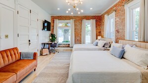 A bedroom with two beds, a sofa, a desk, and a window with curtains. - Art City Inn (Springville)