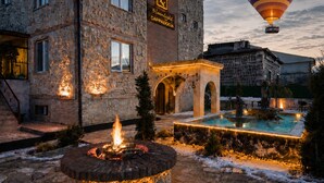 Un patio de hotel con una chimenea, una piscina y un globo aerostático en el cielo.