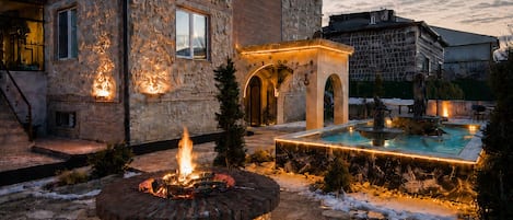 A hotel courtyard with a fire feature, a pool, and a hot air balloon in the sky.