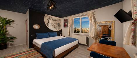 Une chambre à coucher comprenant un lit, un bureau, une chaise, une plante en pot, une fenêtre avec vue et un téléviseur fixé au mur.