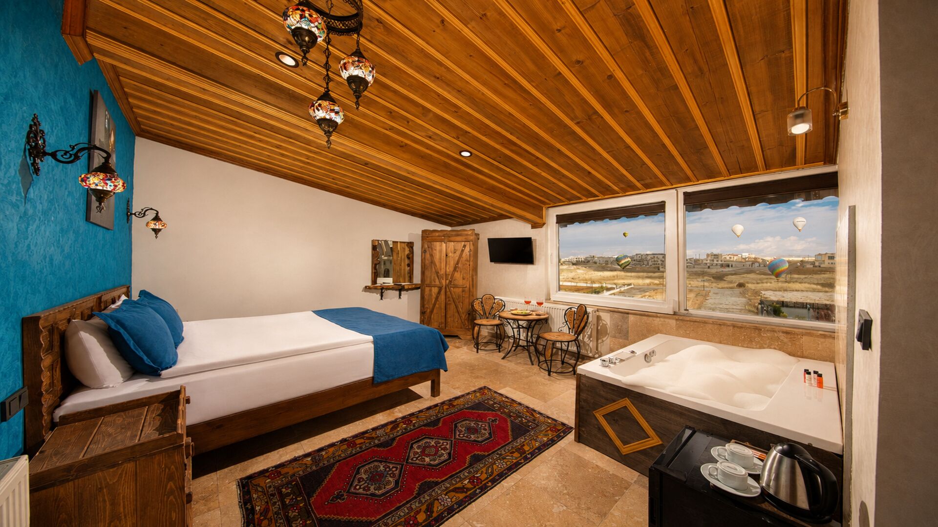 A room with a bed, a small table with chairs, a window with a view, and a bathtub.