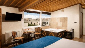 A room with a bed, a window with a city view, a sink, and a television. - Moonlight  Of Cappadocia (Nevsehir)