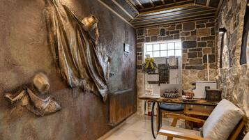 Un interior rústico con paredes de piedra, techo de madera y un comedor con mesa y sillas.