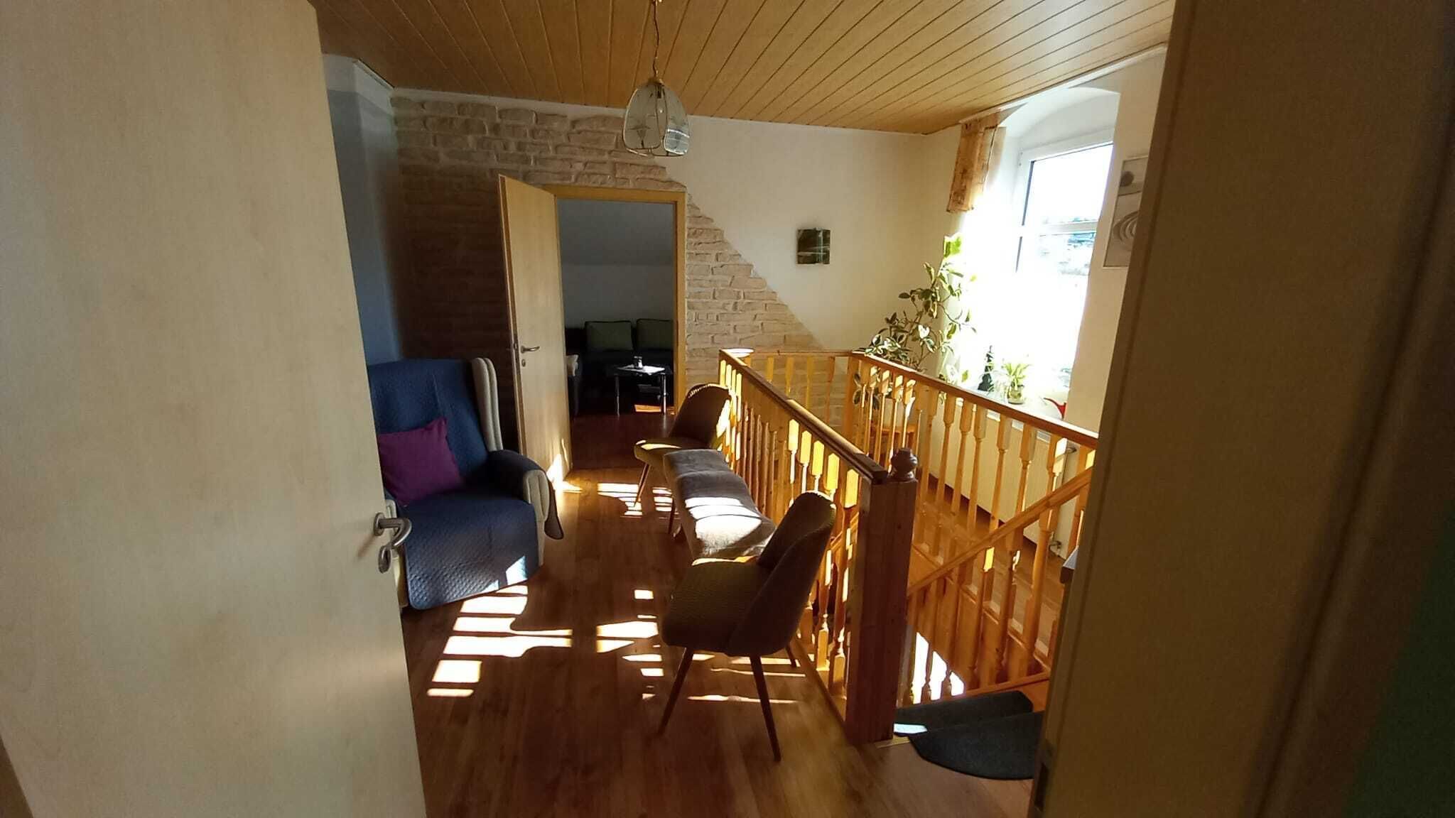 A wooden-floored hallway with a staircase leading to a balcony.