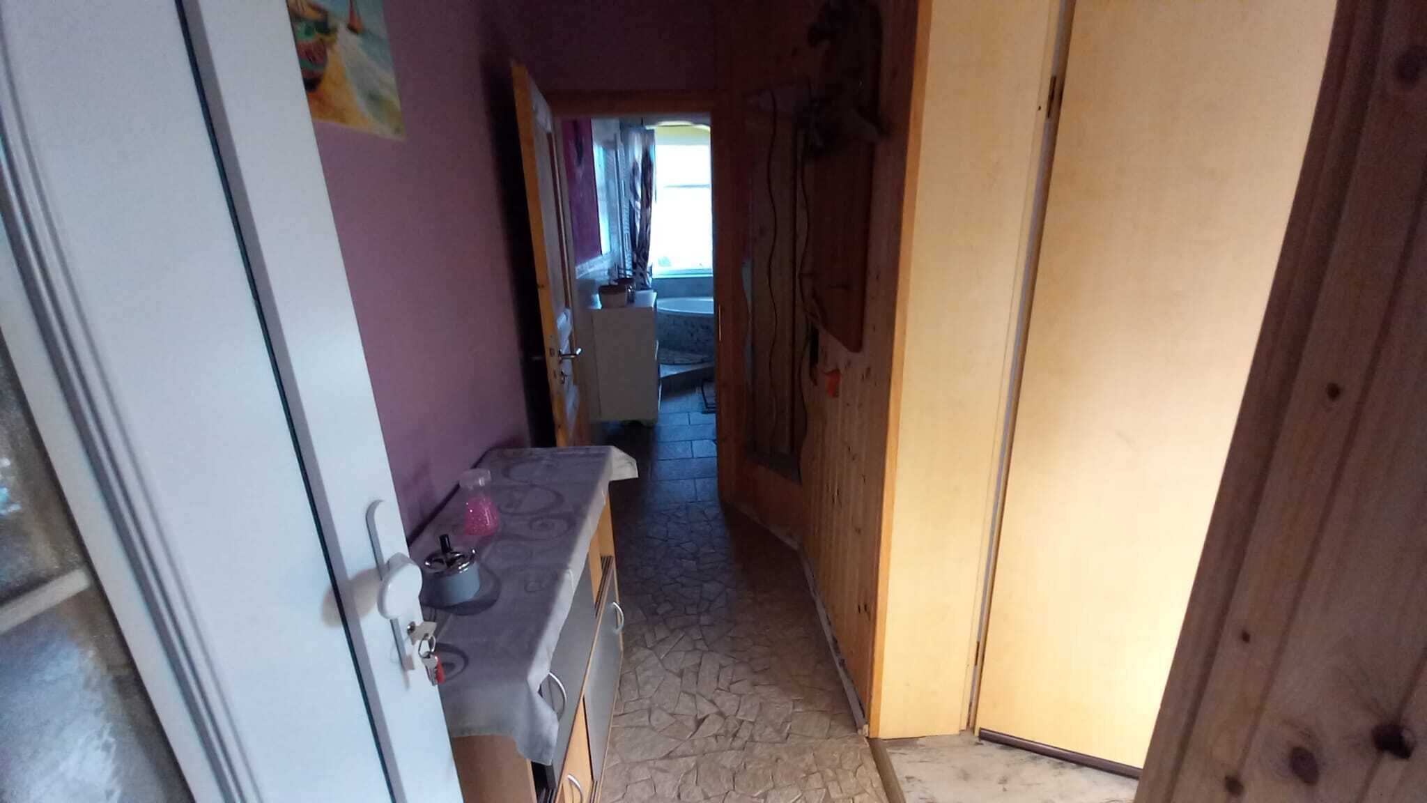 Ein schmaler Flur mit Küchenbereich am Ende, der eine Arbeitsplatte mit Wasserkocher und Spüle zeigt.