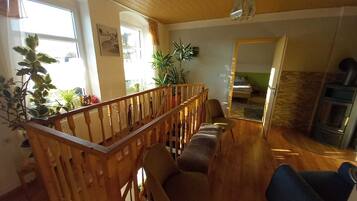 Un saló acollidor amb una escala de fusta, una xemeneia i vista cap a l'habitació veïna.