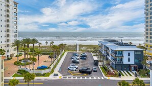 Un hotel sulla costa con parcheggio, palme e vista sull'oceano.