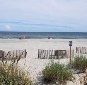 Enjoy the serene beach scene with a clear view of the ocean and a wooden fence bordering the shore.