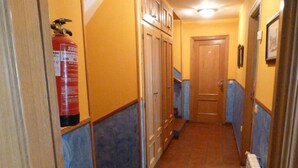 A narrow hallway with blue and yellow walls, wooden cabinets, and a fire extinguisher. - Hotel Mestas (Cabrales)