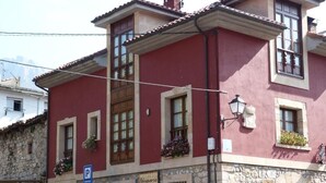 A red building with stone facade, multiple windows, and outdoor seating. - Hotel Mestas (Cabrales)