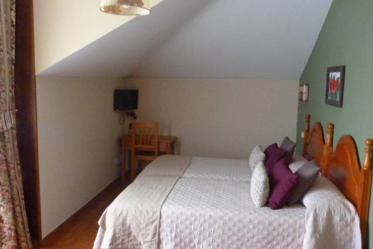 A bedroom with a bed, a chair, a television, and a picture on the wall.