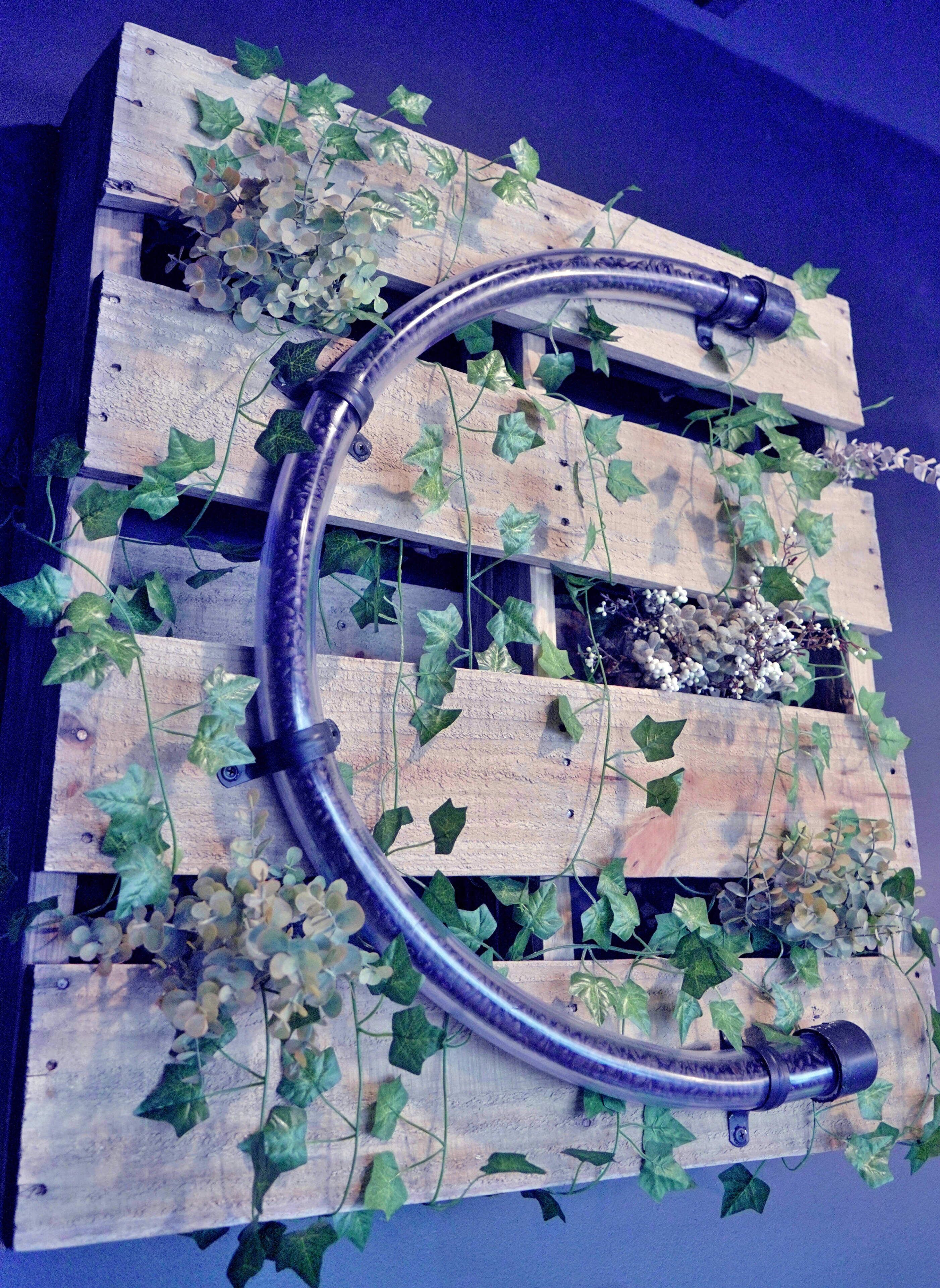 A wooden structure with a curved metal pipe, surrounded by ivy.