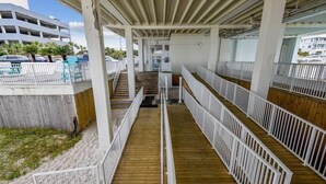 A covered wooden deck with white railings, leading to a staircase. - Studio condo on beach at Historical Fontainebleau Terrace. Sleeps 4.Full Kitchen (Panama City Beach)