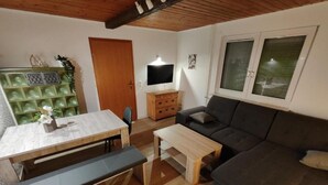 Een gezellige woonkamer met een houten tafel, een bank en een televisie.