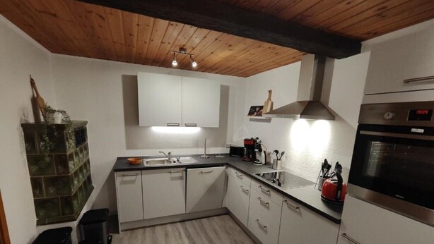 Een moderne keuken met witte kasten, een zwart aanrecht en roestvrijstalen apparatuur.