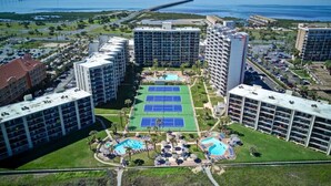 A hotel with multiple high-rise buildings, a tennis court, and a pool area.