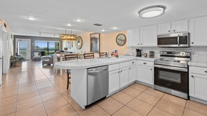 A modern kitchen with white cabinets, stainless steel appliances, and a large island with a dishwasher.