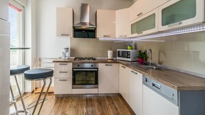 A modern kitchen with a gas stove, oven, microwave, and built-in dishwasher. There are two bar stools and a window with a view.