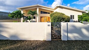 A modern two-story house with a beige facade, a wooden door, and a black decorative gate. - Villa with Private Pool and Jacuzzi / Sea View (Cas Abou)
