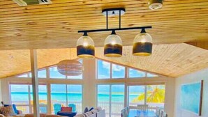 Een ruime keuken met een groot eiland, moderne hanglampen en uitzicht op de oceaan.
