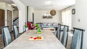 A modern dining area with a long table, chairs, and a central vase with flowers. - Awesome home in Labin (Labin)