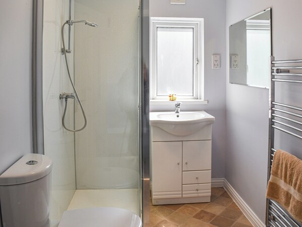 Une salle de bain avec une douche à parois de verre, un lavabo blanc et un porte-serviettes.