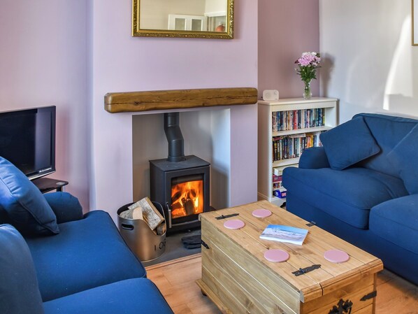 Una sala de estar acogedora con chimenea, sofás azules, una mesa de centro de madera y una estantería.