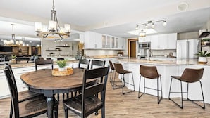 Una cocina moderna con armarios blancos, una isla central y un comedor con una mesa redonda y sillas.
