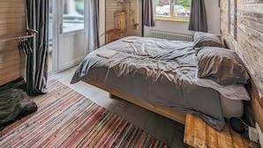 A bedroom with a bed, a window, a radiator, and a wooden ceiling. - 2 bedroom accommodation in Rye (Rye)