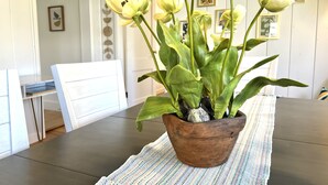 Ein Blumentopf mit grünen Blättern und weißen Blüten auf einem Tisch.
