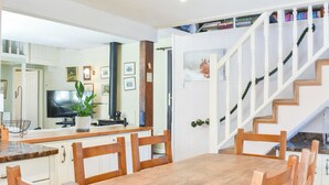 A dining area with a wooden table and chairs, a television, a plant, and a staircase leading to a loft. - 2 bedroom accommodation in Snaizeholme, near Hawes (Snaizeholme, near Hawes)