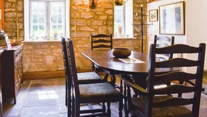 A rustic dining room with stone walls, wooden furniture, and a large window providing natural light. - 3 bedroom accommodation in Skelton, near Penrith (Skelton, near Penrith)