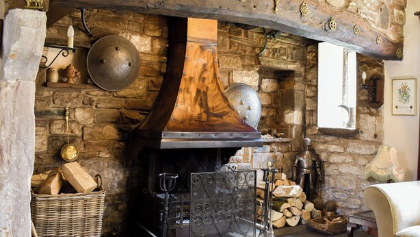 A stone fireplace with a large chimney, a metal grate, and a rustic wooden mantel. - 3 bedroom accommodation in Skelton, near Penrith (Skelton, near Penrith)