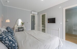 Ein Schlafzimmer mit Bett, Schreibtisch, Spiegel, Fernseher und Kleiderschrank.