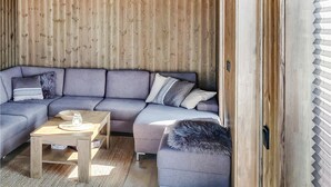 A modern living room with a sectional sofa, a small wooden table, and a furry ottoman.