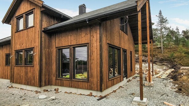 A modern wooden house with large windows and a covered porch.