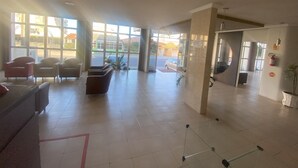 Un vestíbulo amplio con diseño moderno, que cuenta con una recepción, zona de estar y ventanas grandes con vistas al exterior.