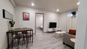 Un salon moderne comprenant un coin repas, un canapé, un téléviseur et une plante en pot.