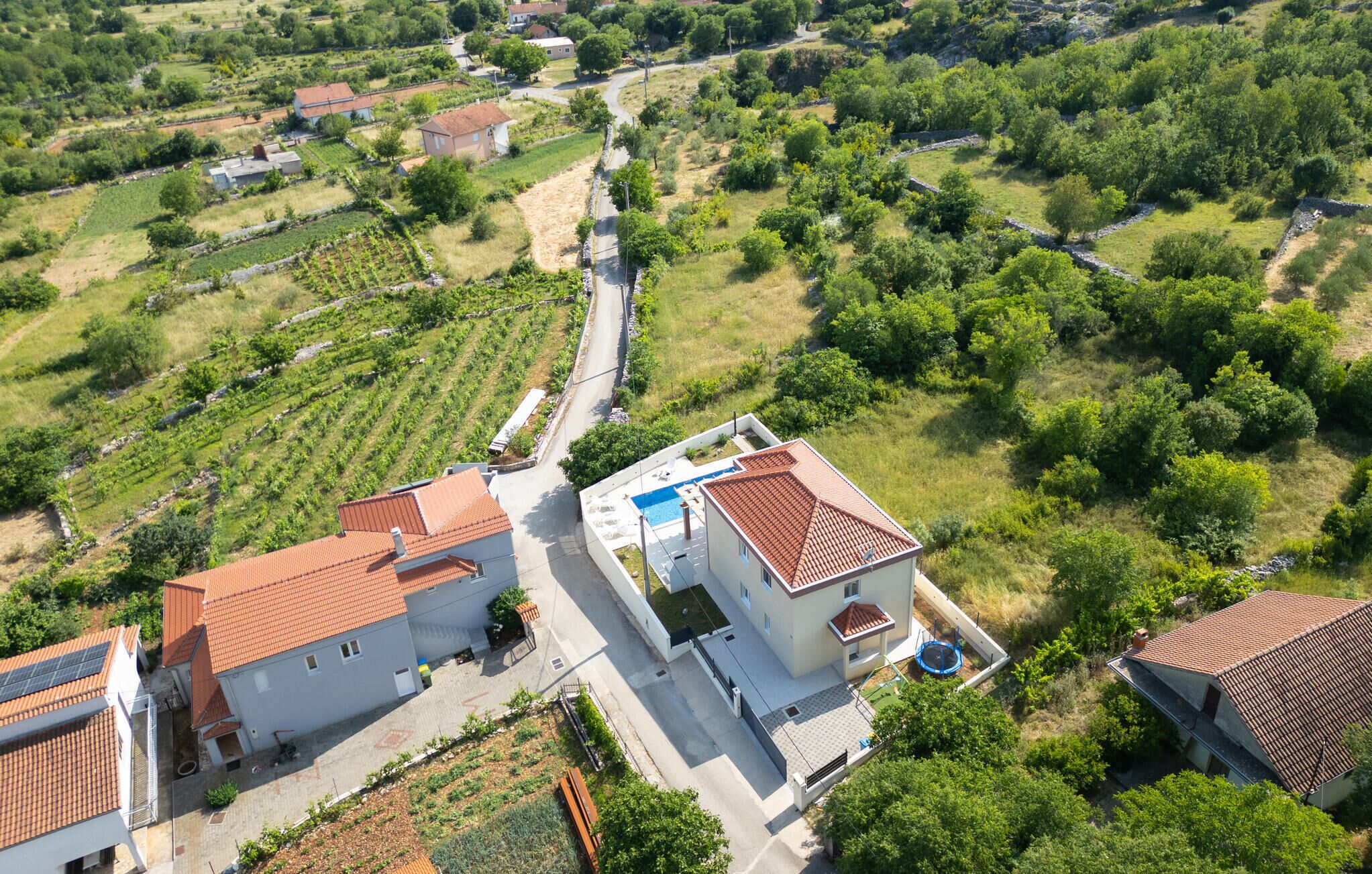 A residential area with houses, a road, and surrounding greenery.