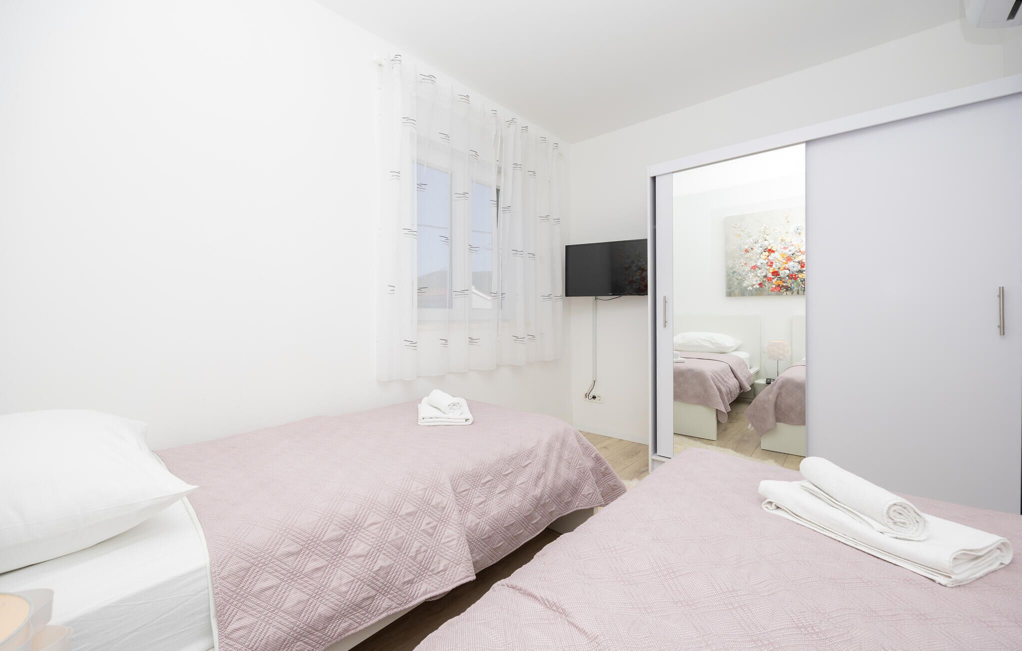 Un dormitorio con dos camas, un televisor y una puerta corrediza que da a un baño.