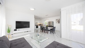 Un salon moderne avec un téléviseur à écran plat, une table basse en verre et un canapé.