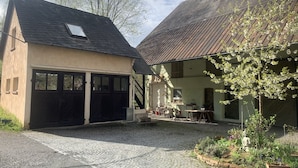 A courtyard with cobblestone paths, a garage, and a building with a sloped roof.