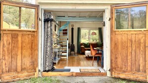 A wooden door leading to a room with a staircase, a sofa, and a window.