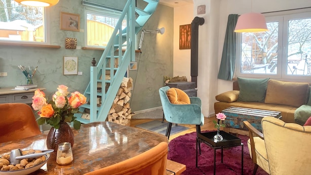 A cozy living room with a blue staircase, a coffee table with a vase of flowers, and a comfortable sofa.