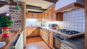 A kitchen with wooden cabinets, a tiled backsplash, a stove, and a sink. - Gorgeous apartment in Saint-Chely-d'Aubrac (Saint-Chely-d'Aubrac)