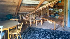A rustic wooden room with a sloped ceiling, wooden chairs, a round table, and a patterned rug. - 2 bedroom stunning home in Figeholm (Figeholm)