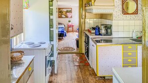 A narrow kitchen with a stove, sink, and cabinets. There is a dining area with a table and chairs visible through an open doorway. - 2 bedroom stunning home in Figeholm (Figeholm)