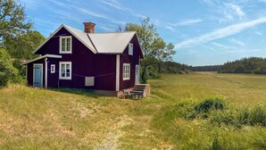 A two-story house with a red exterior, a chimney, and a small porch with steps leading up to the entrance. - 2 bedroom stunning home in Figeholm (Figeholm)